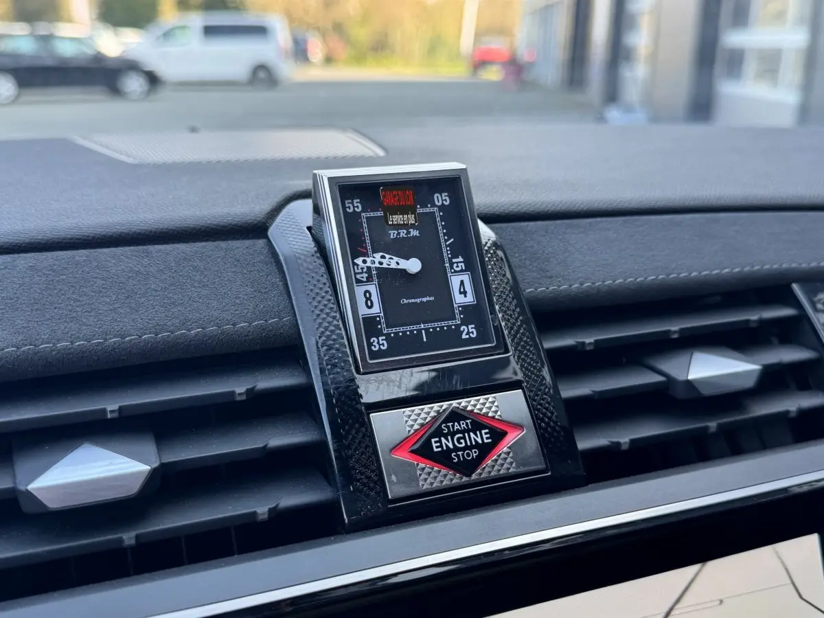 Gros plan sur le tableau de bord du DS7 Crossback blanc, mettant en valeur l'horloge B.R.M et le bouton start/stop rouge.
