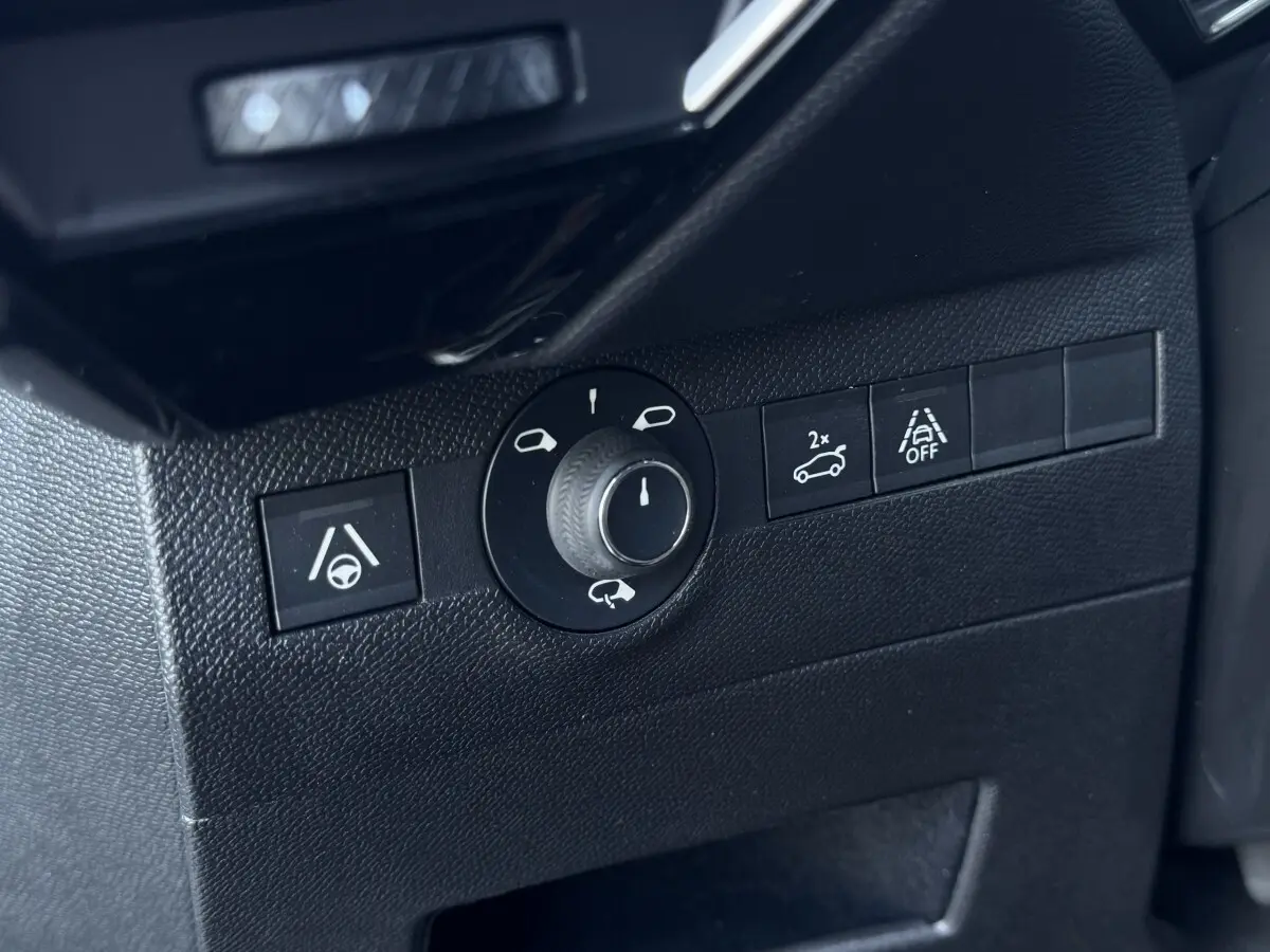 Gros plan sur les commandes de réglage des rétroviseurs et d'assistance à la conduite dans un DS7 Crossback blanc.