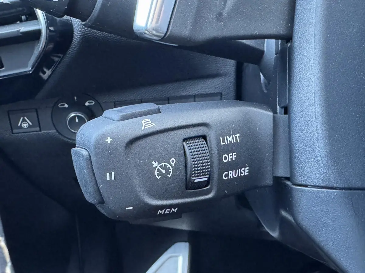 Gros plan sur la commande de régulateur de vitesse du DS7 Crossback blanc, côté gauche du volant.