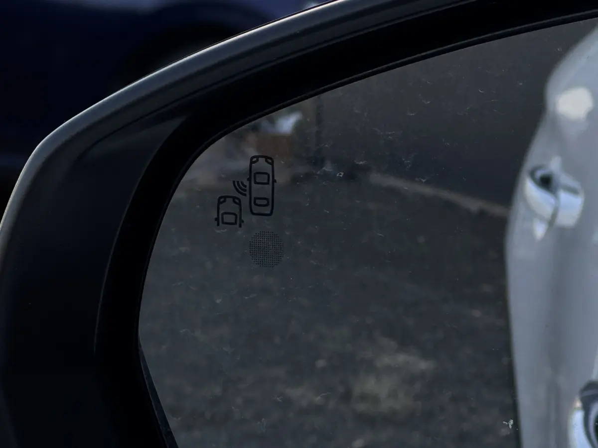 Gros plan sur le rétroviseur côté conducteur d’un DS7 Crossback blanc, avec indication du système d’alerte d’angle mort.