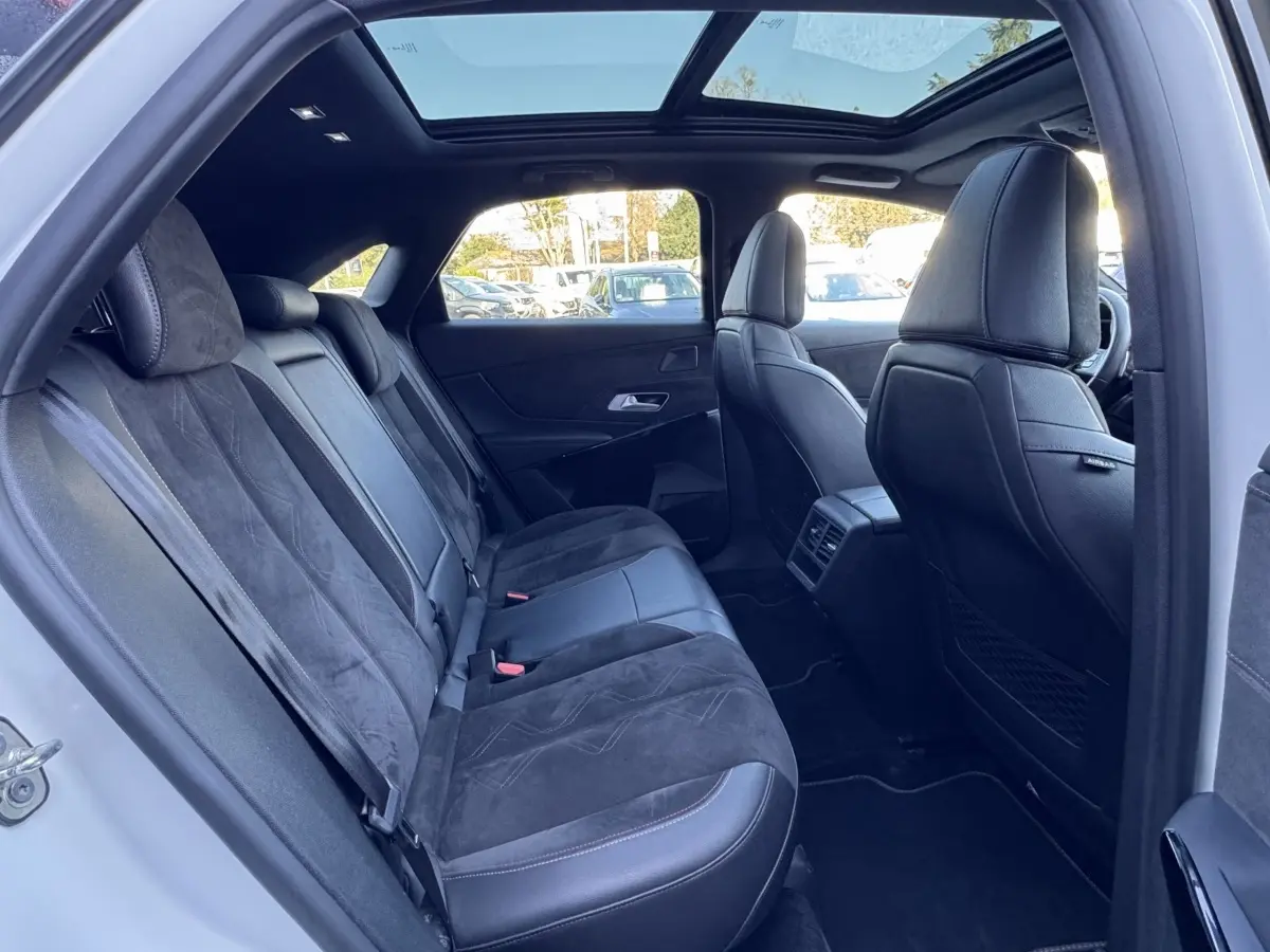 Vue intérieure côté gauche montrant les sièges arrière en cuir noir et alcantara avec toit panoramique du DS7 Crossback blanc.