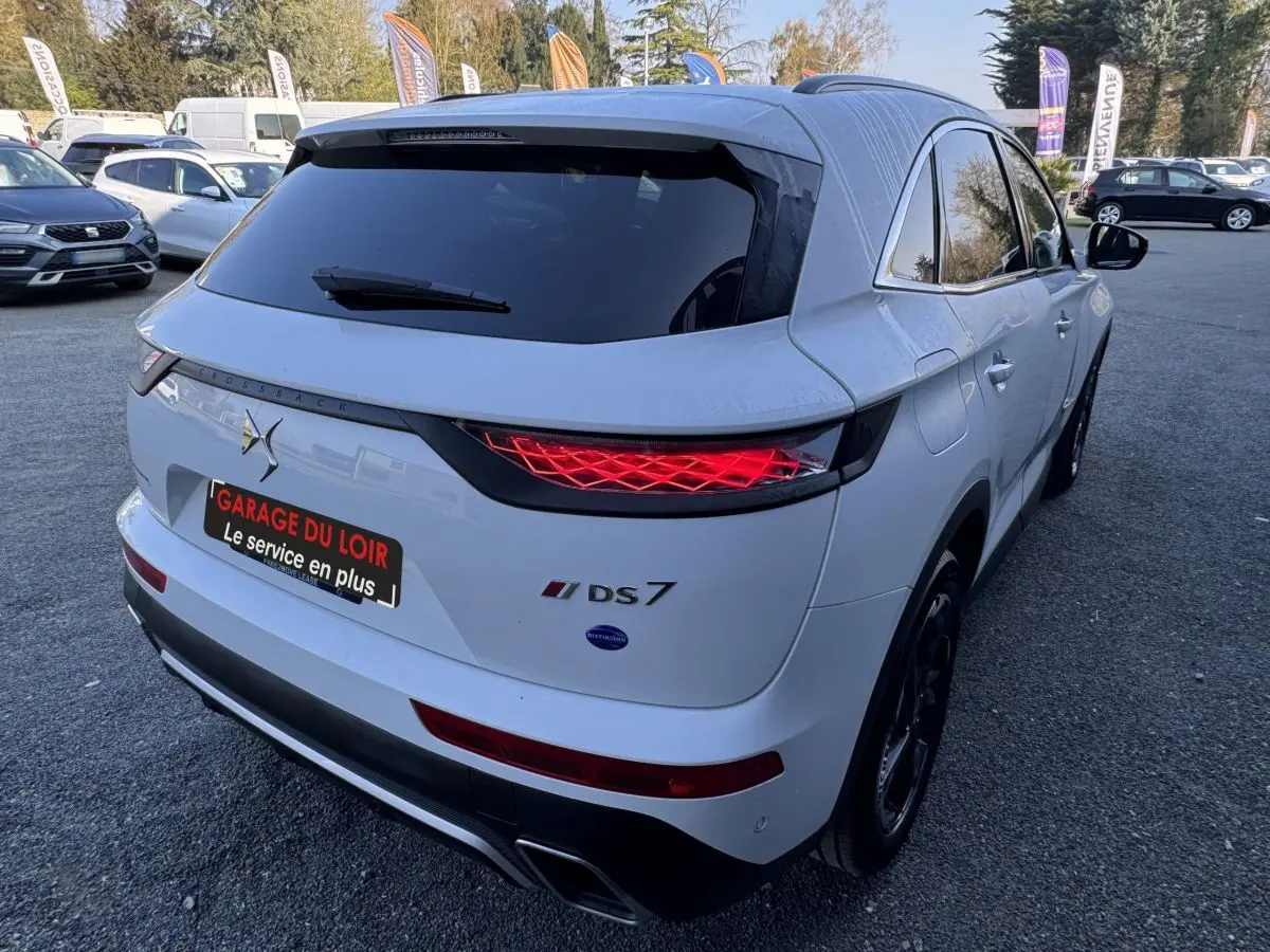 Vue 3/4 arrière droite d'un DS7 Crossback blanc avec feux arrière LED et toit noir brillant.