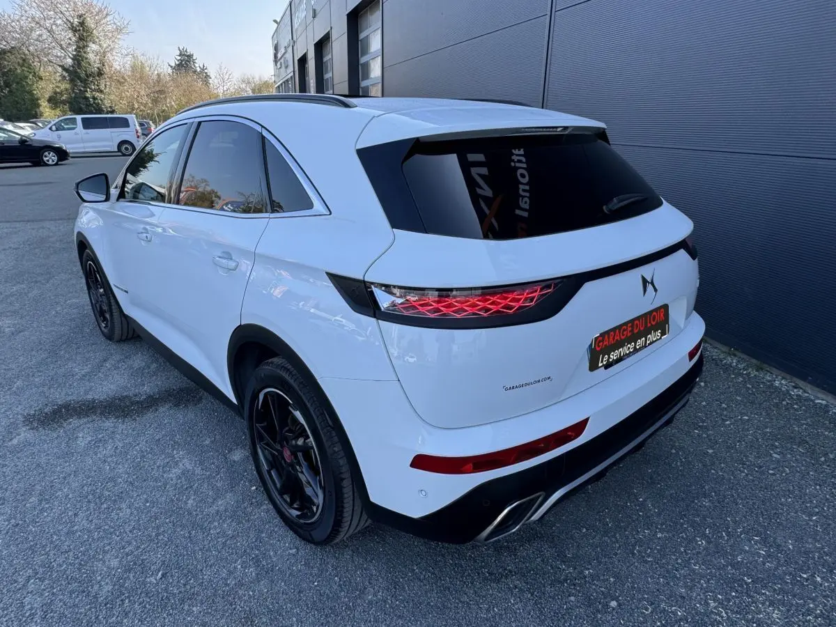Vue 3/4 arrière droite du DS7 Crossback blanc avec jantes noires et feux arrière LED distinctifs.