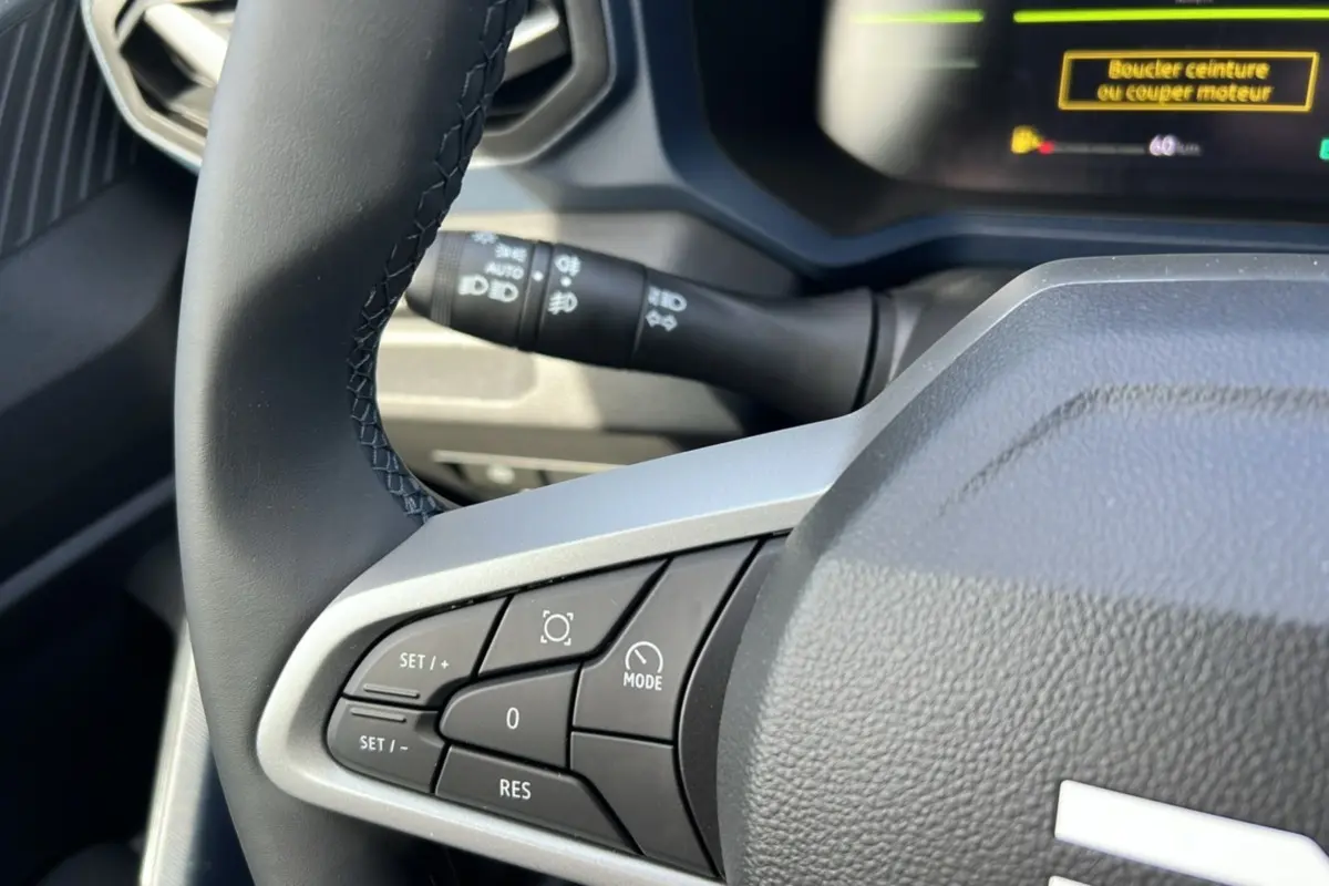 Gros plan sur le volant cuir noir du Dacia Bigster Hybrid 155 Expression Plus avec commandes intégrées côté gauche.
