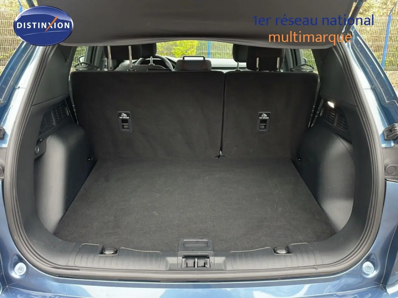 Vue arrière du coffre ouvert d'un Ford Kuga 2024 bleu chrome métal, montrant un espace de chargement propre et spacieux.