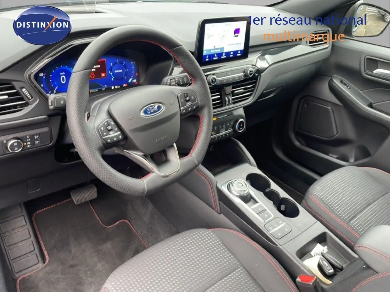 Vue intérieure côté conducteur du Ford Kuga 2024, tableau de bord moderne avec écran tactile et volant cuir noir à surpiqûres rouges.