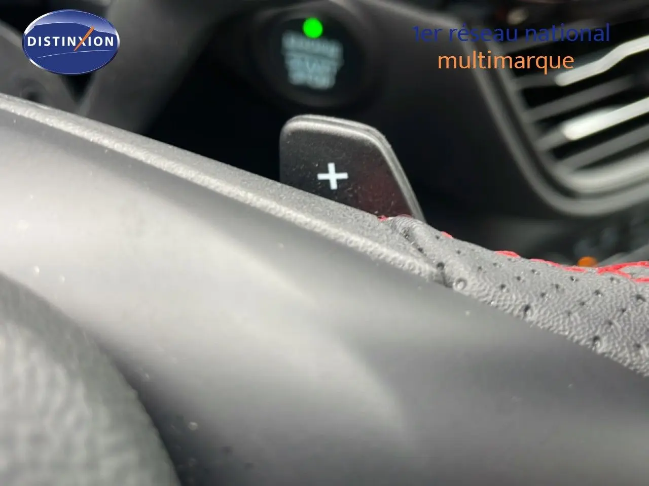 Gros plan sur la palette de changement de vitesse "+" en aluminium noir et cuir perforé avec surpiqûres rouges dans un Ford Kuga 2024.