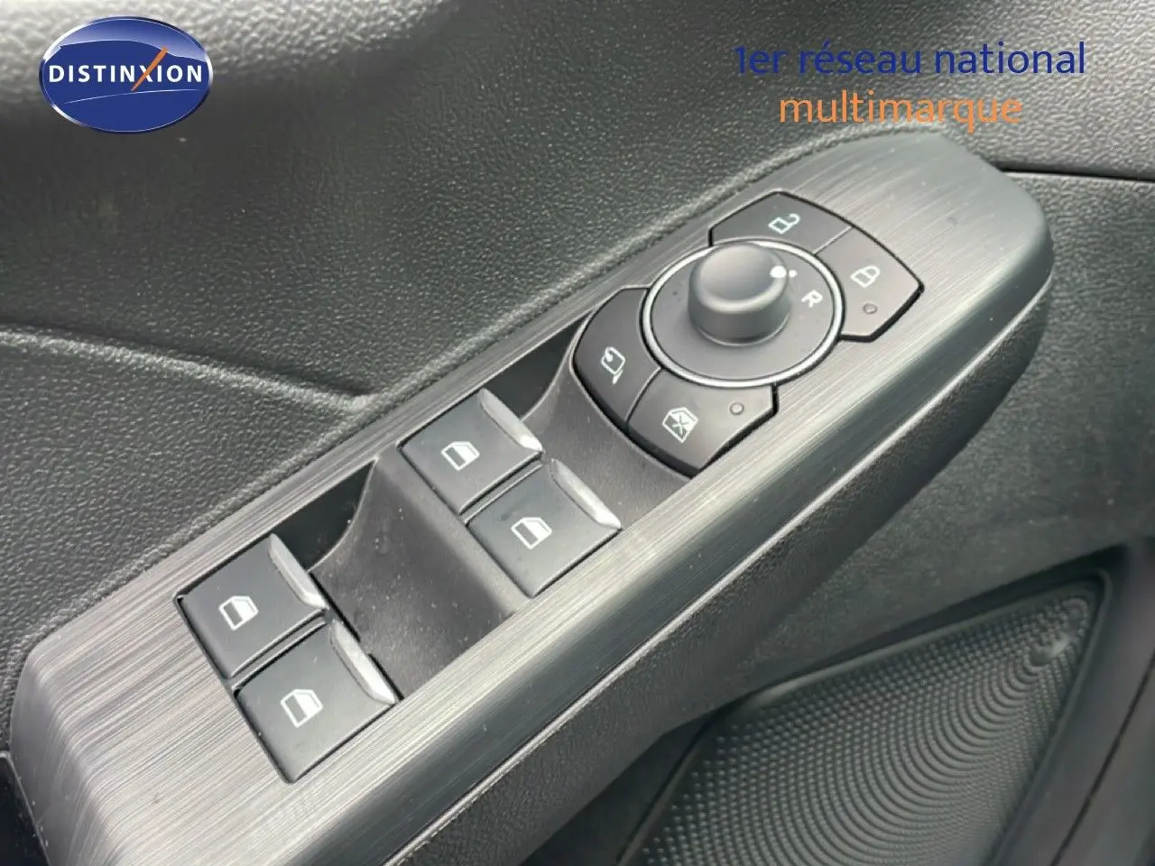 Gros plan sur les commandes des vitres et rétroviseurs côté conducteur du Ford Kuga 2024 bleu chrome.