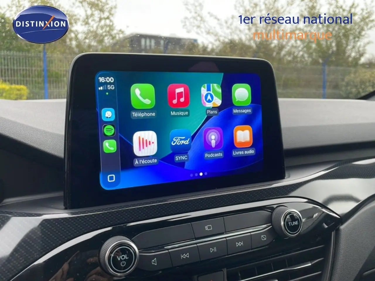 Écran tactile central du Ford Kuga 2024 en bleu chrome, affichant l'interface multimédia avec commandes audio et navigation.