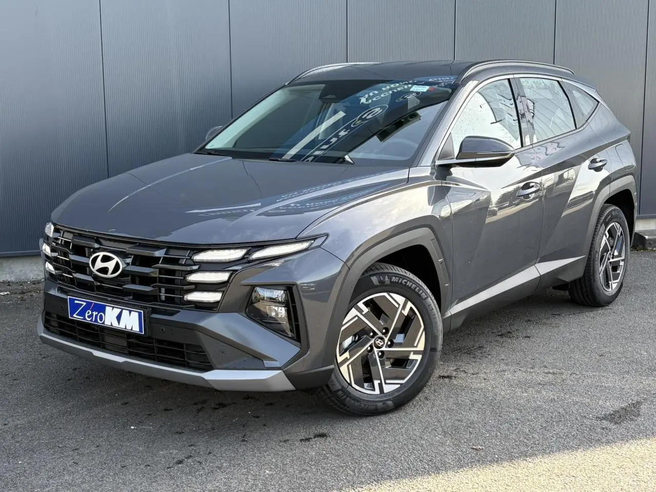 Vue 3/4 avant droite du Hyundai Tucson 2025 gris Ecotronic avec jantes alliage et calandre distinctive.
