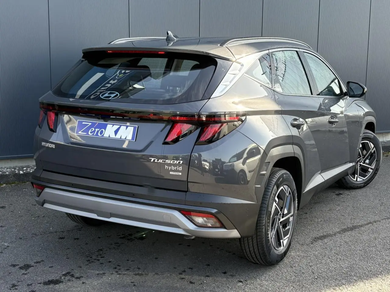 Vue 3/4 arrière droite du Hyundai Tucson 2025 gris Ecotronic avec feux arrière LED et jantes alliage 17 pouces.