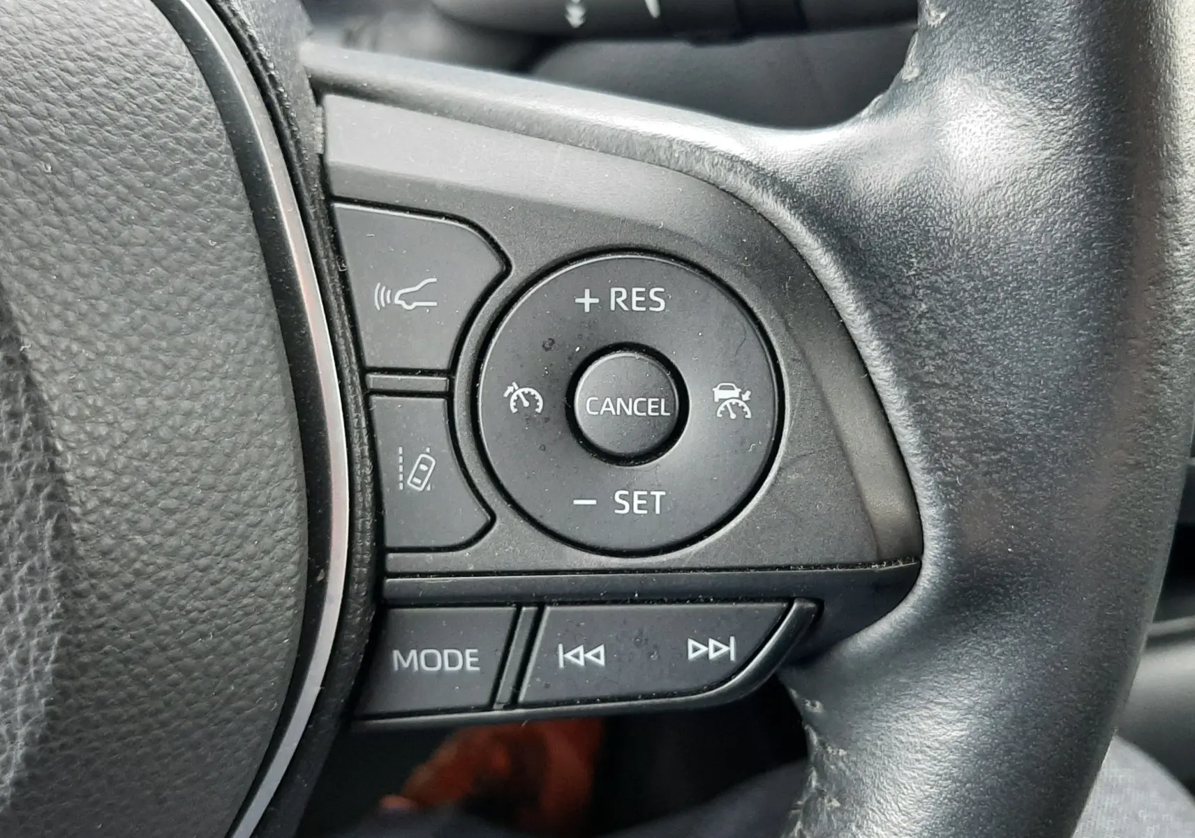 Gros plan sur les commandes noires du volant côté droit d'une Toyota Corolla blanche hybride 2022.