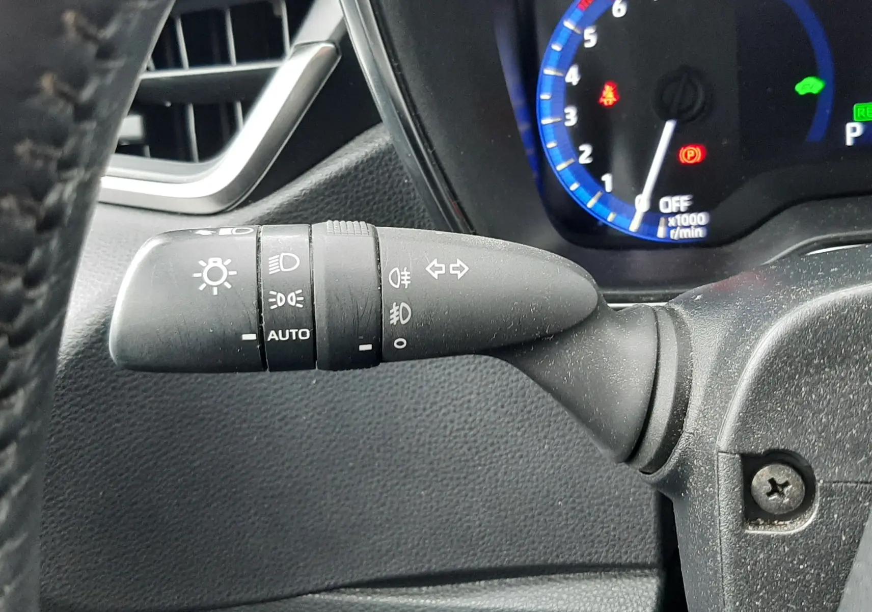 Gros plan sur la commande des phares et clignotants à gauche du volant dans une Toyota Corolla blanche 2022 hybride.