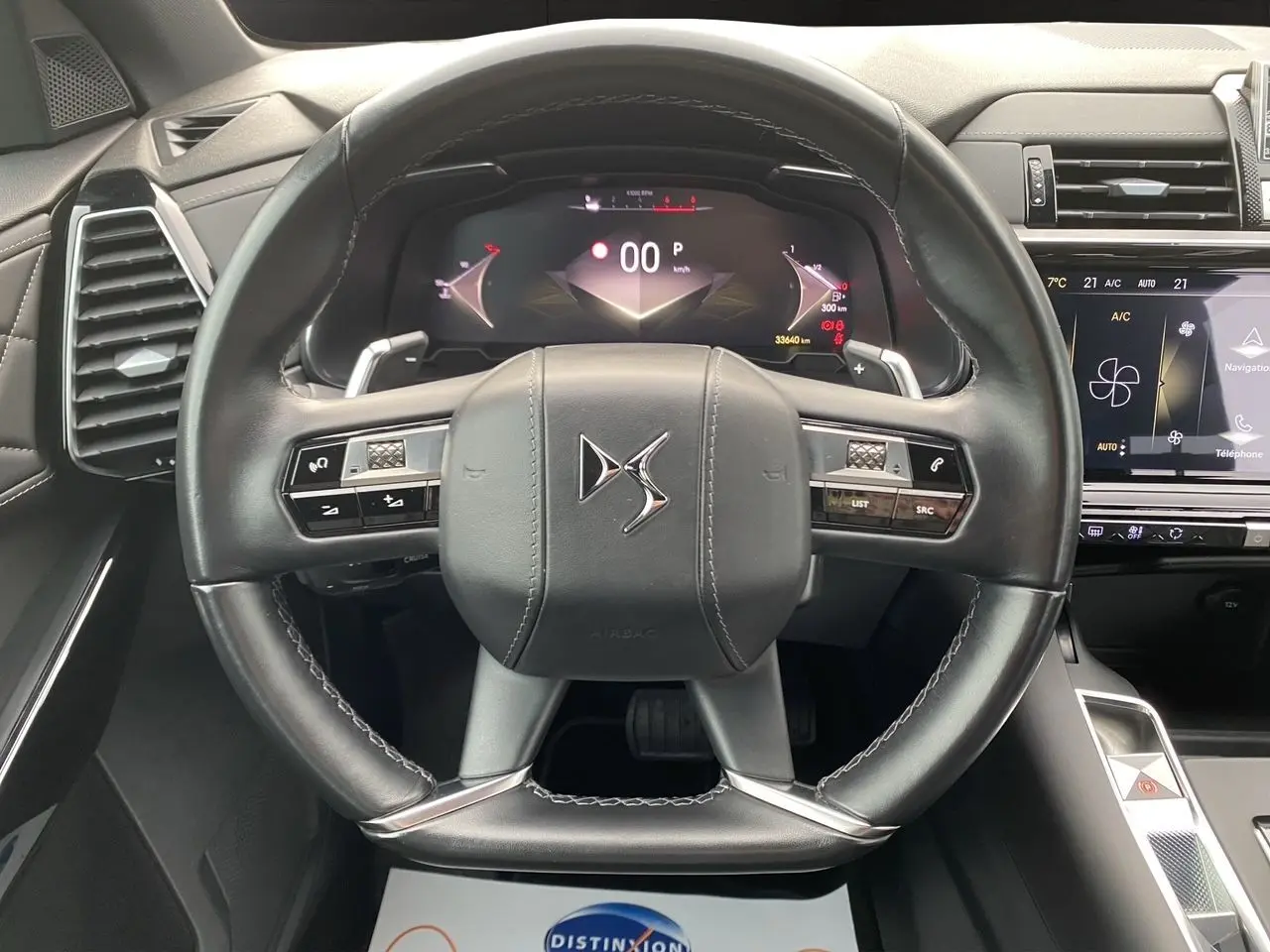 Vue rapprochée du volant en cuir noir du DS7 2024 avec tableau de bord numérique et écran tactile central.