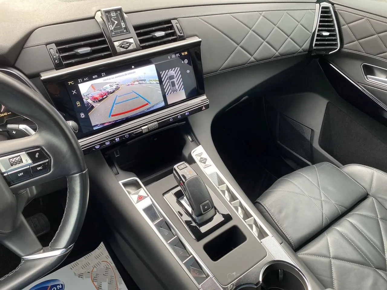 Vue intérieure du poste de conduite du DS7 Bleu Eclipse, mettant en valeur la sellerie cuir noire, la montre BRM et l'écran tactile central.