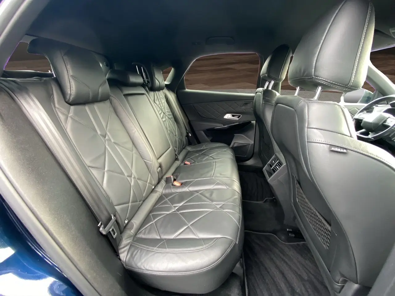 Vue intérieure arrière côté droit du DS7 2024 bleu Eclipse, avec sellerie cuir noir électrique et finitions élégantes.