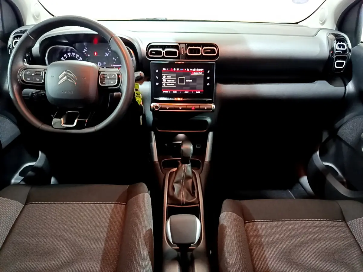 Vue intérieure avant du Citroën C3 Aircross avec tableau de bord noir et écran tactile central lumineux.