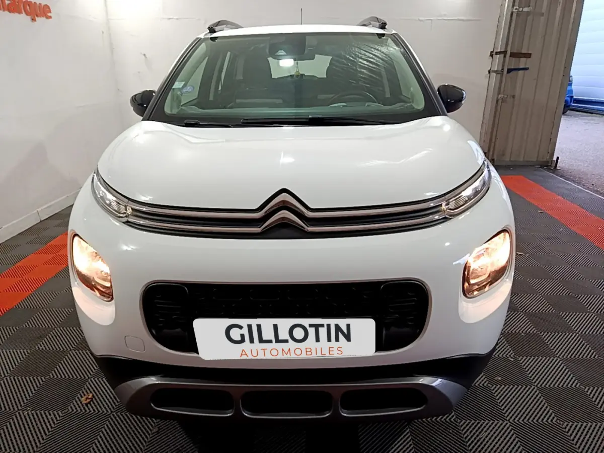 Vue frontale d'un Citroën C3 Aircross blanc avec phares allumés et calandre noire distinctive.