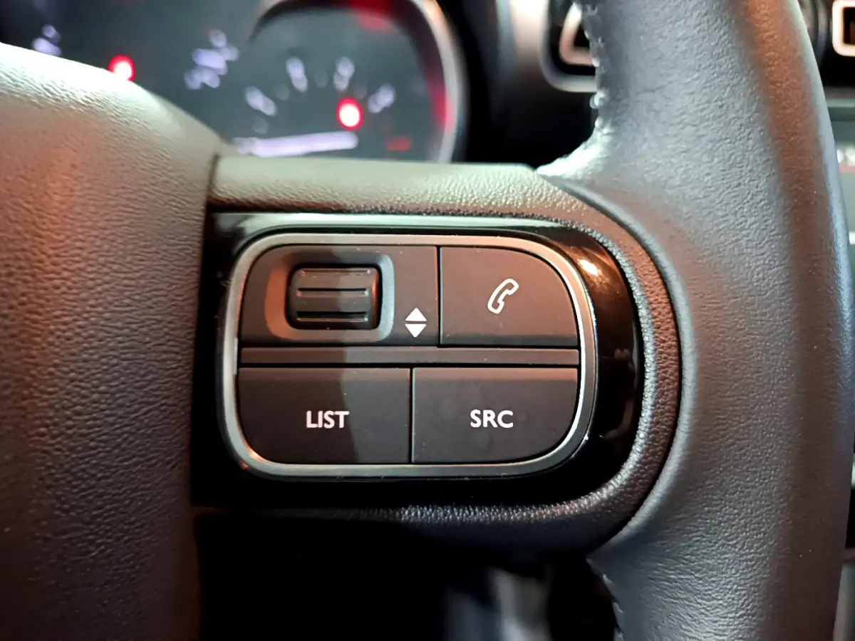 Gros plan sur les commandes gauche du volant cuir du Citroën C3 Aircross 2019, boutons LIST et SRC visibles.