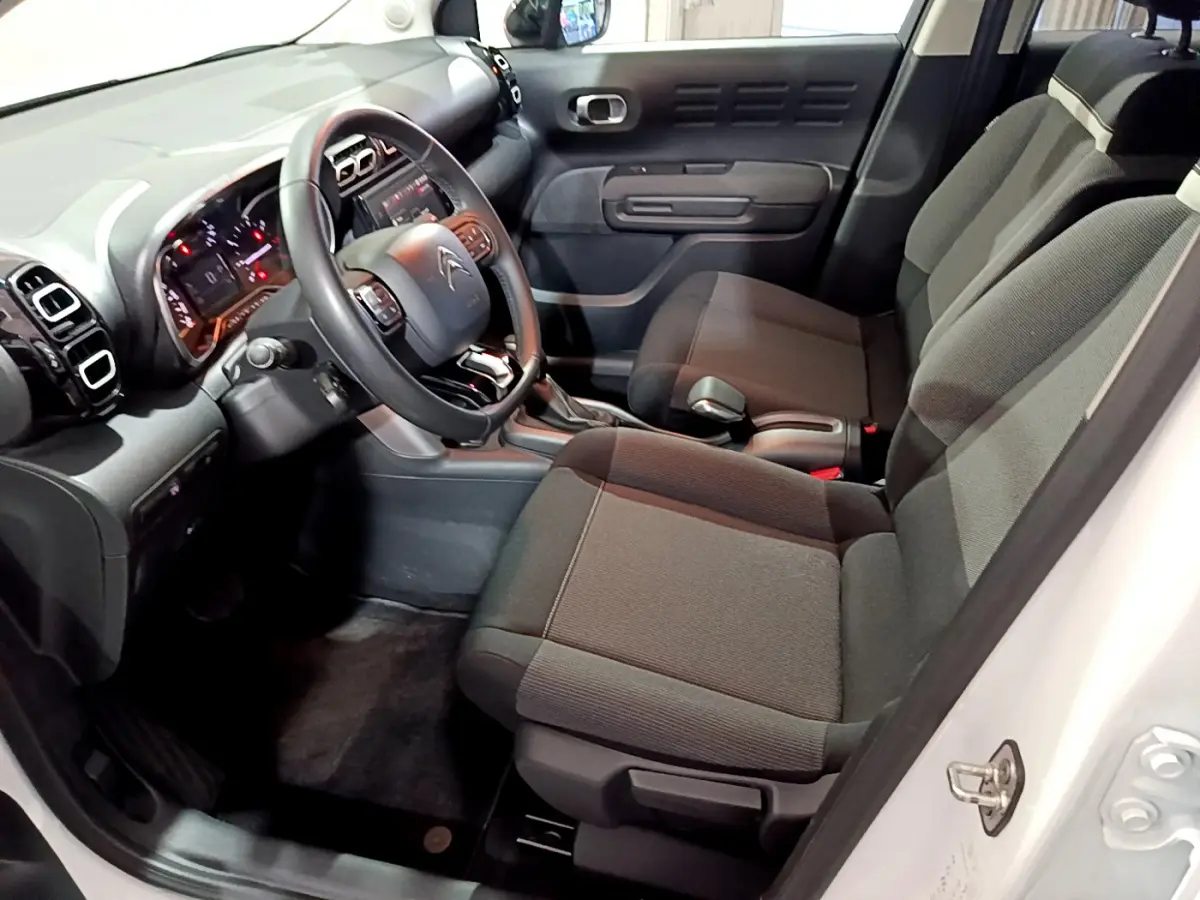 Intérieur avant droit du Citroën C3 Aircross blanc 2019, montrant sièges tissu gris et tableau de bord noir.