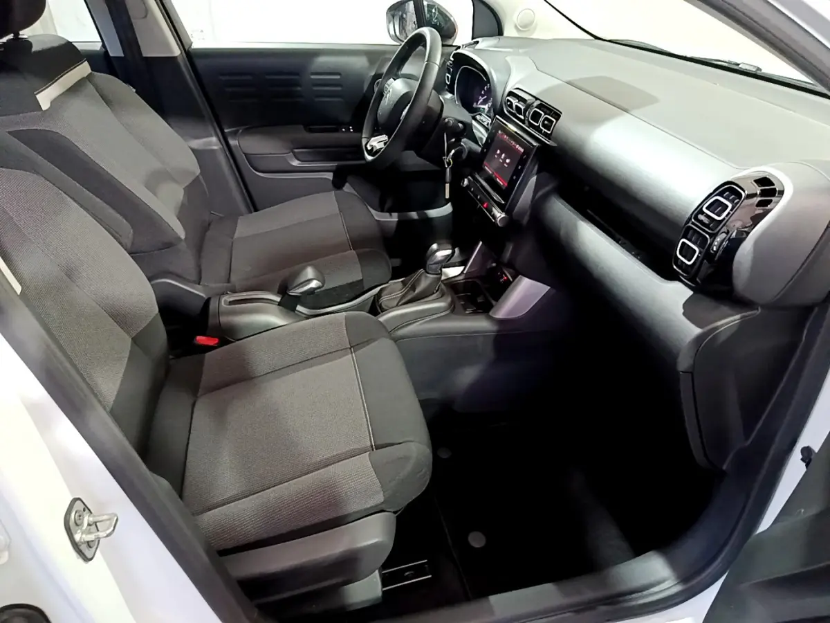 Intérieur avant droit du Citroën C3 Aircross blanc 2019 avec sièges tissu noirs et écran tactile central.