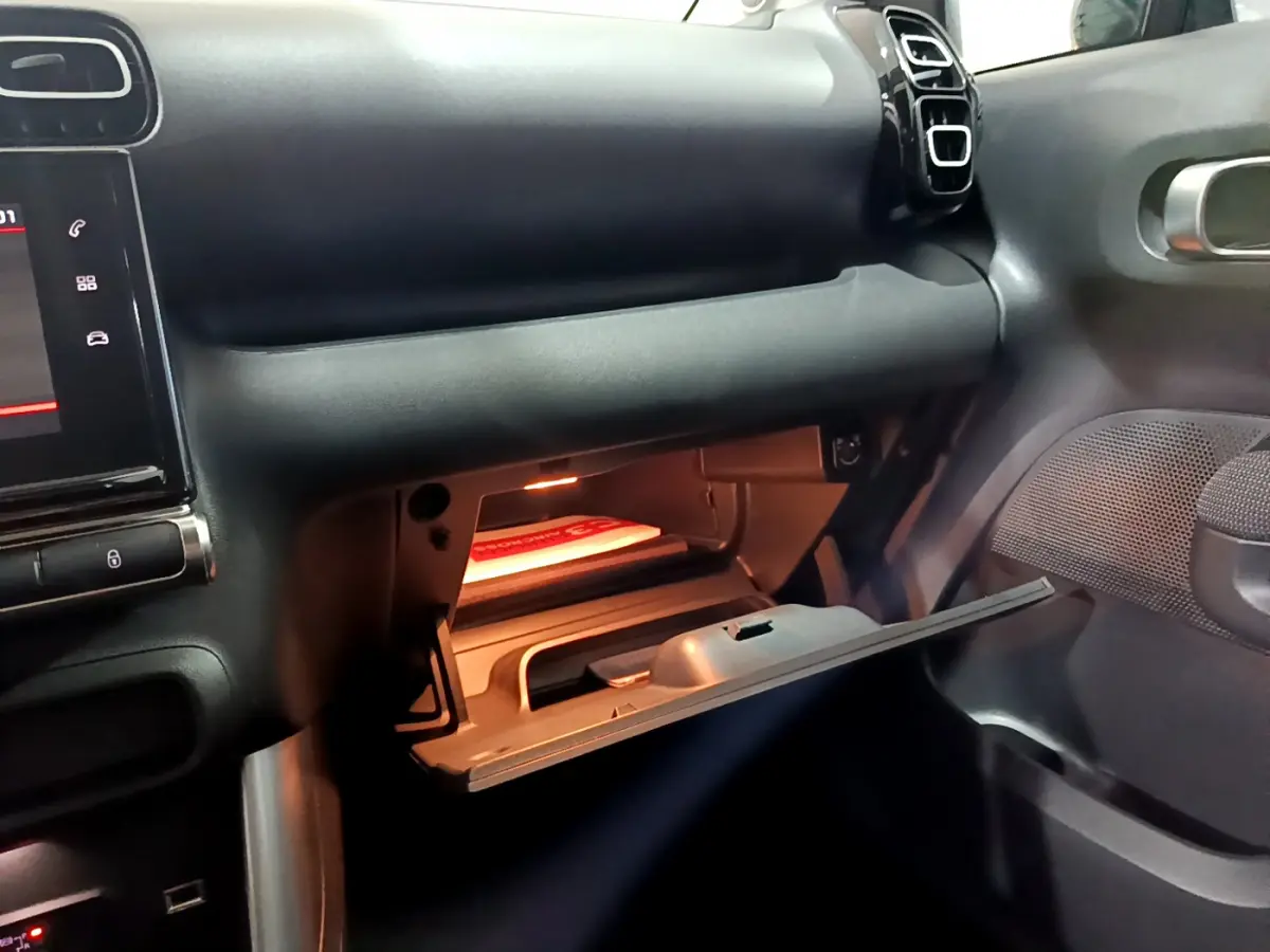 Intérieur du Citroën C3 Aircross 2019, vue du côté passager avec boîte à gants ouverte et tableau de bord noir.