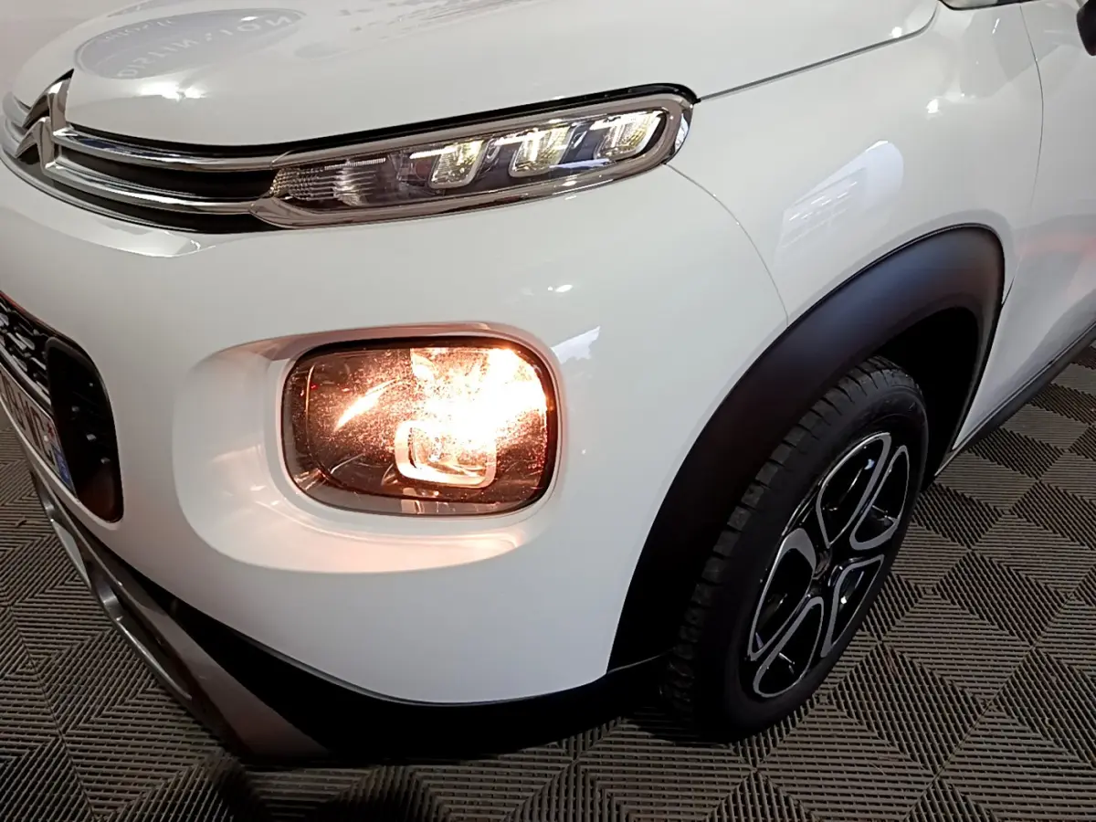 Gros plan sur l'avant droit blanc d'une Citroën C3 Aircross 2019 avec phare antibrouillard allumé et jante noire.