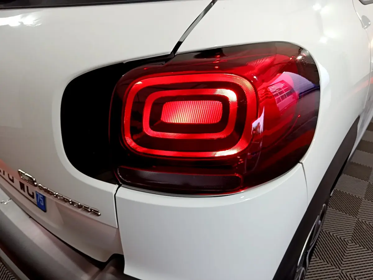 Gros plan sur le feu arrière droit rouge d'un Citroën C3 Aircross blanc, avec logo et partie arrière visibles.