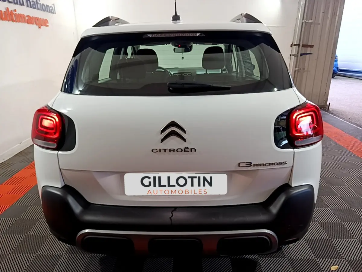 Vue arrière d'un Citroën C3 Aircross blanc avec feux arrière allumés et logo visible sur porte de coffre.