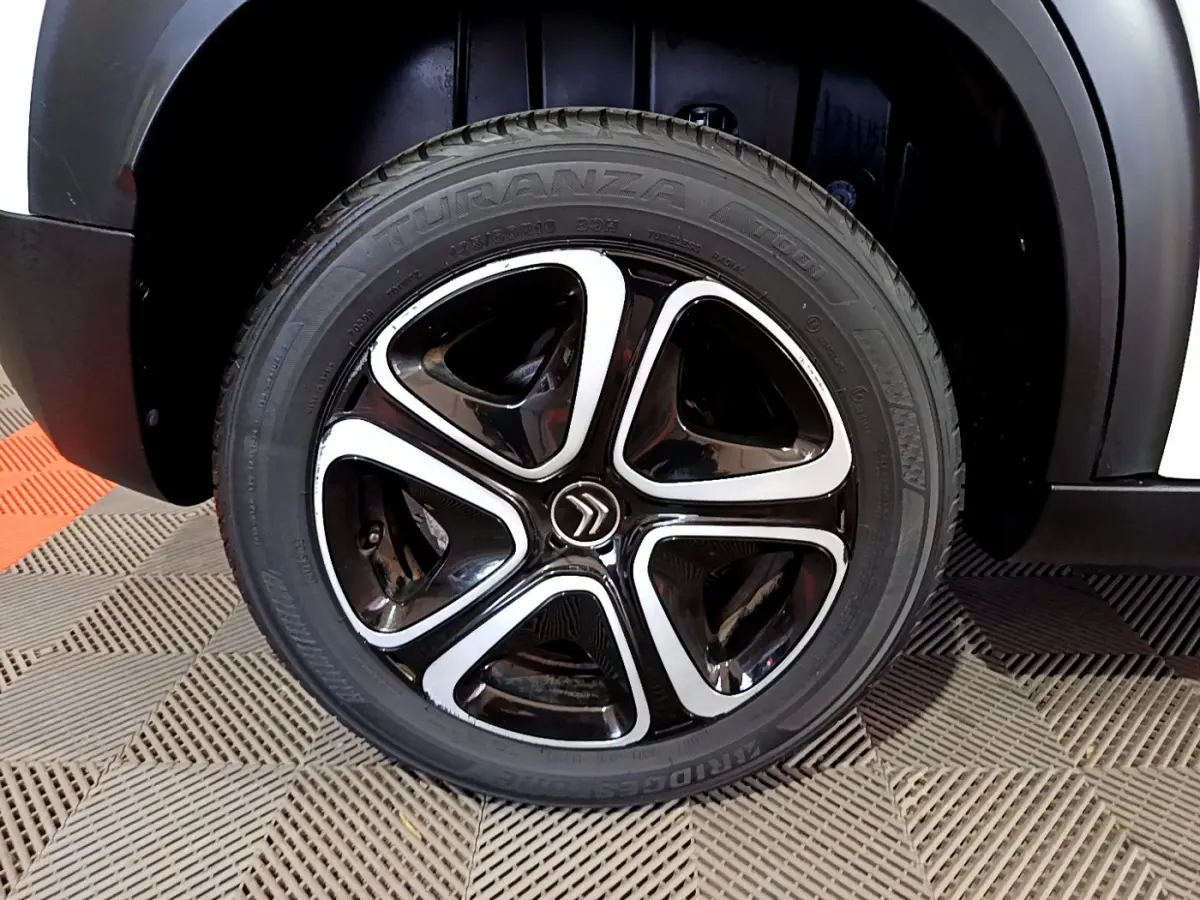 Gros plan sur la roue avant droite d'un Citroën C3 Aircross blanc avec jante noire et argentée au design distinctif.