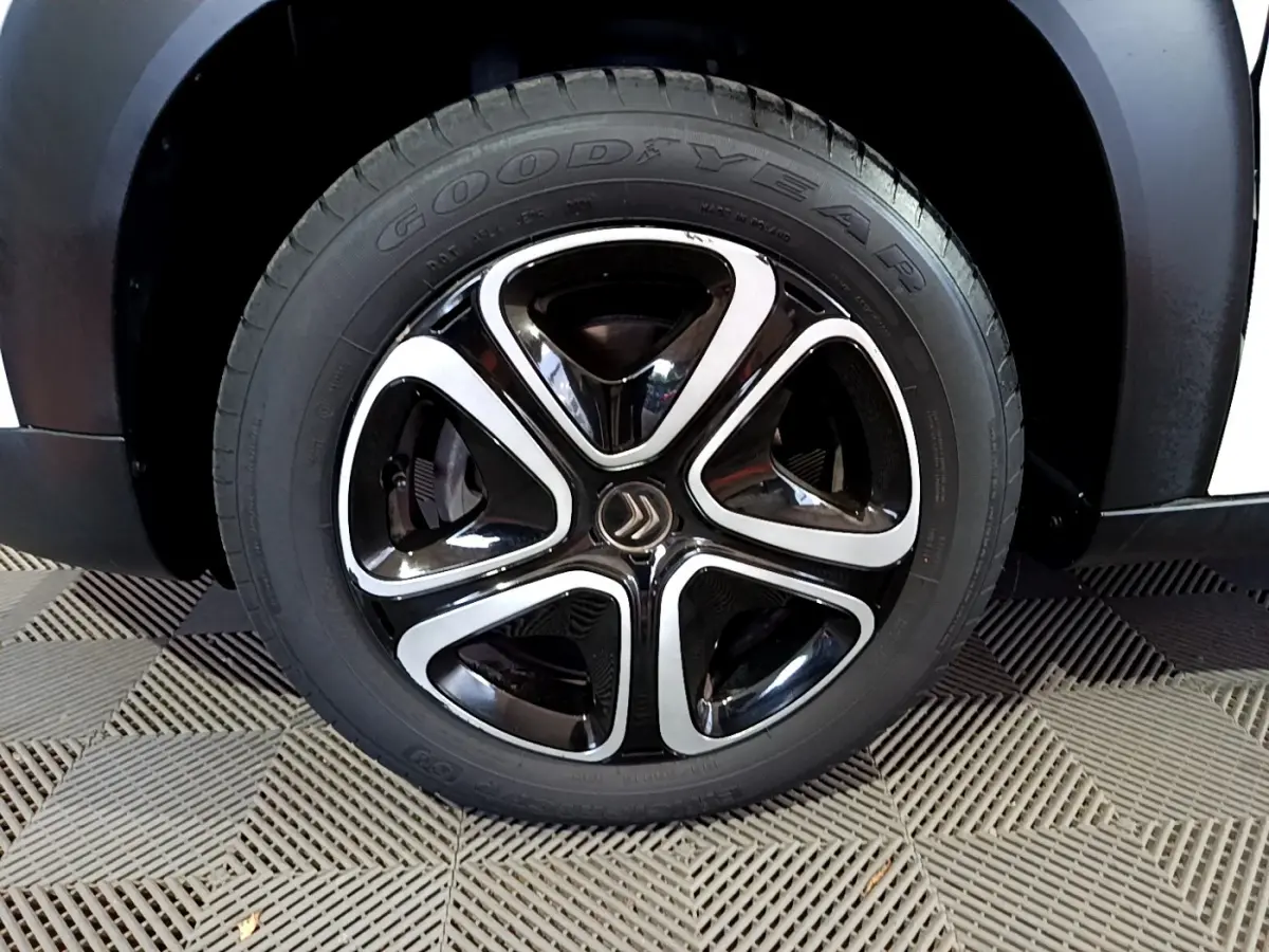 Gros plan sur la roue avant droite blanche du Citroën C3 Aircross avec jante noire et argentée au design distinctif.