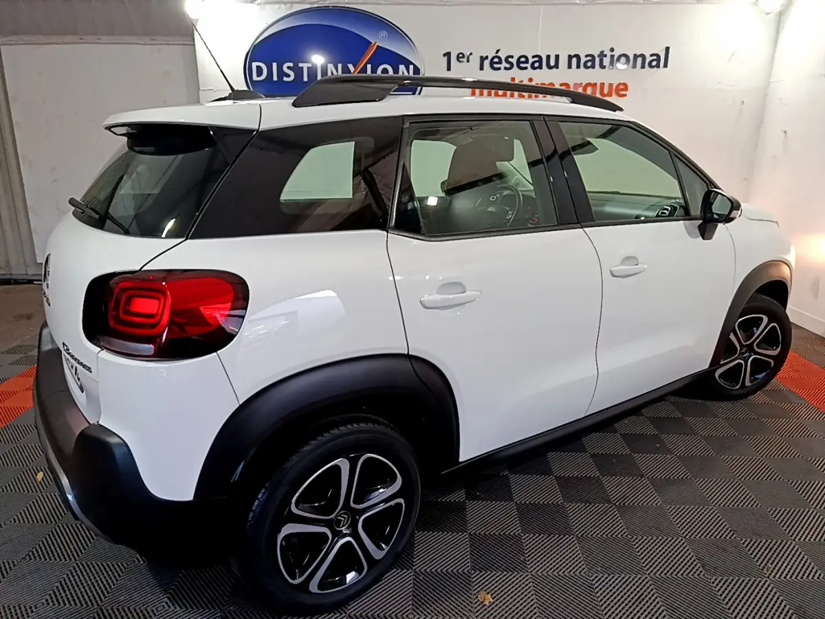 Vue 3/4 arrière droite d'un Citroën C3 Aircross blanc avec toit noir et jantes alliage distinctives.