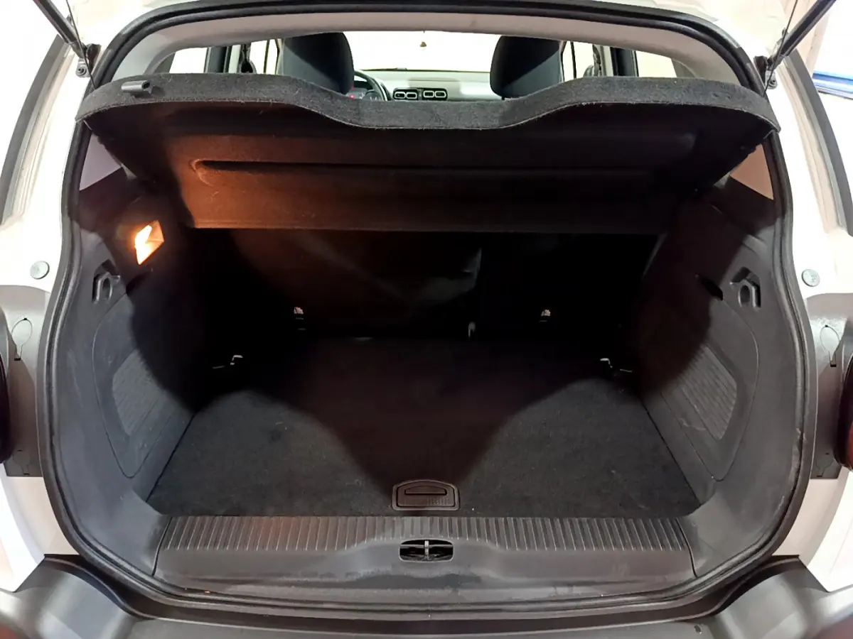 Coffre ouvert d'une Citroën C3 Aircross blanc, vue arrière montrant l'espace de chargement avec tablette de séparation.