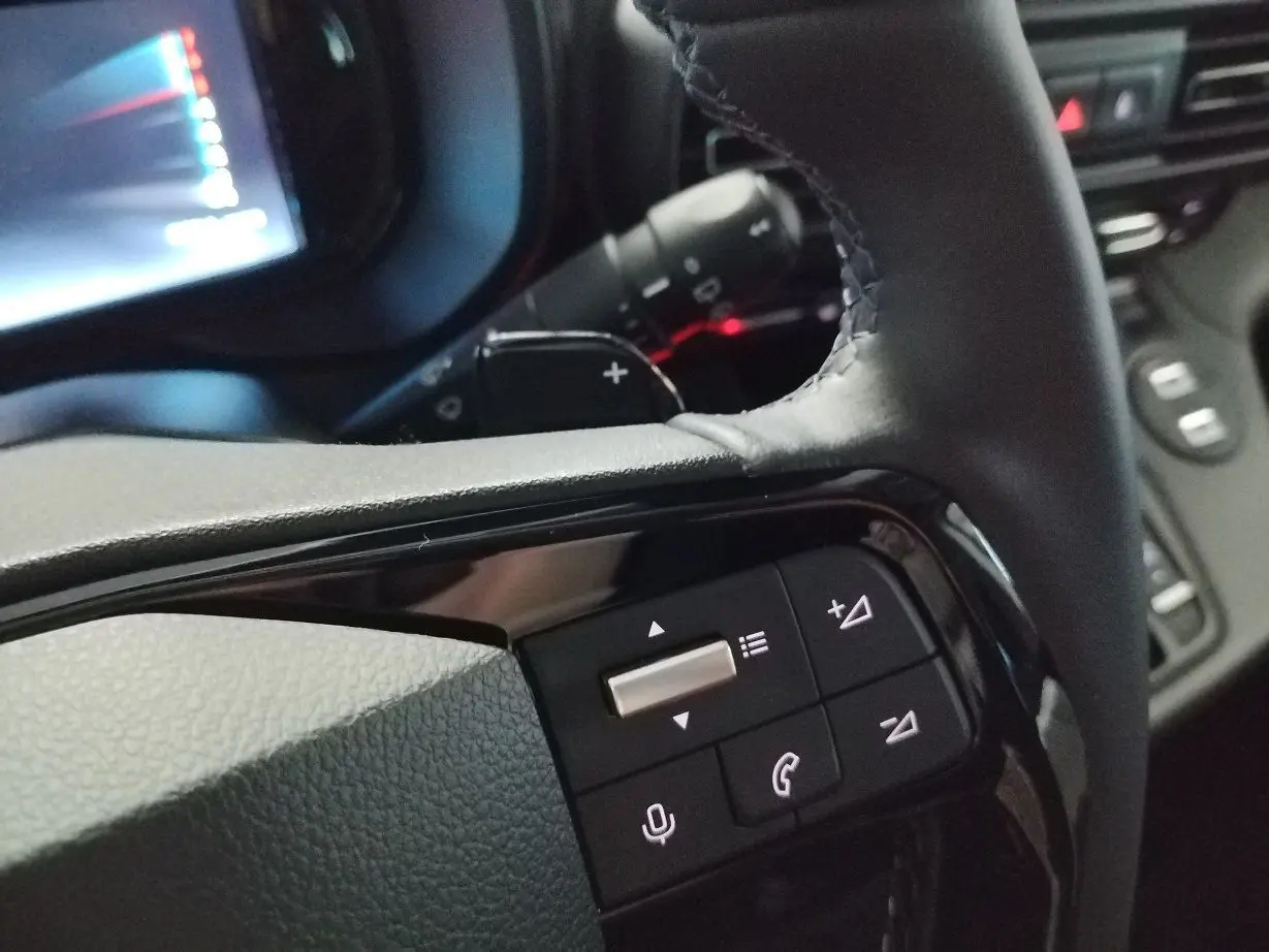 Gros plan sur les commandes multifonctions noires du volant du Citroën Berlingo 2025, intérieur sombre.