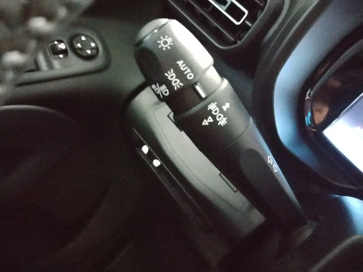 Gros plan sur la commande des feux et clignotants noire dans l’habitacle du Citroën Berlingo blanc 2025.