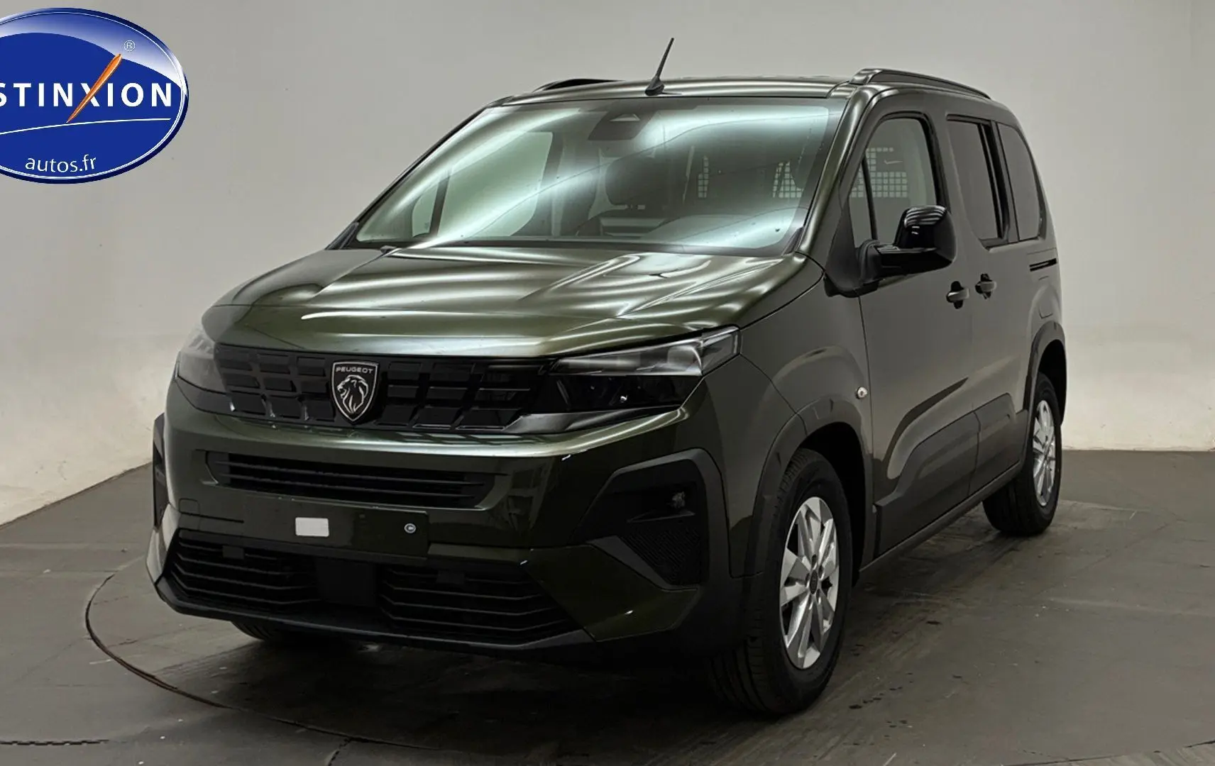 Vue 3/4 avant du Peugeot Rifter 2026 vert Sirkka avec barres de toit et jantes alliage 16 pouces.