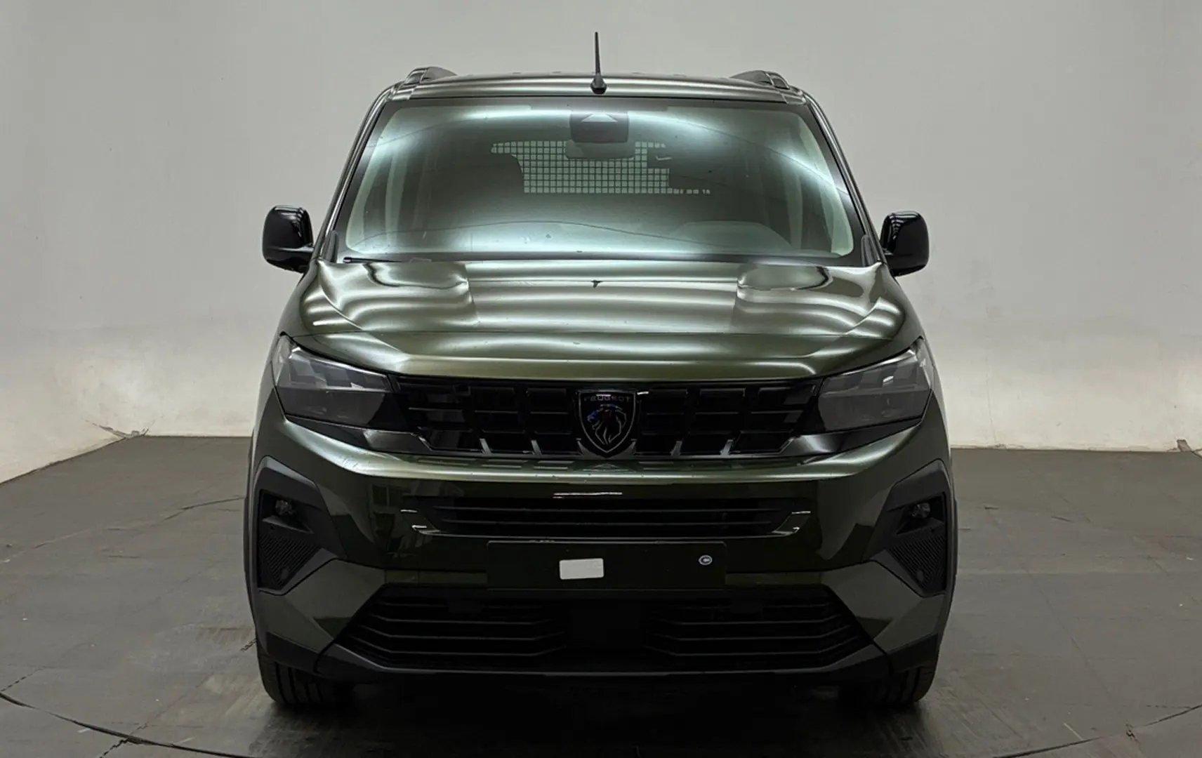 Vue frontale d'un Peugeot Rifter 2026 vert Sirkka avec calandre noire et logo lion central.