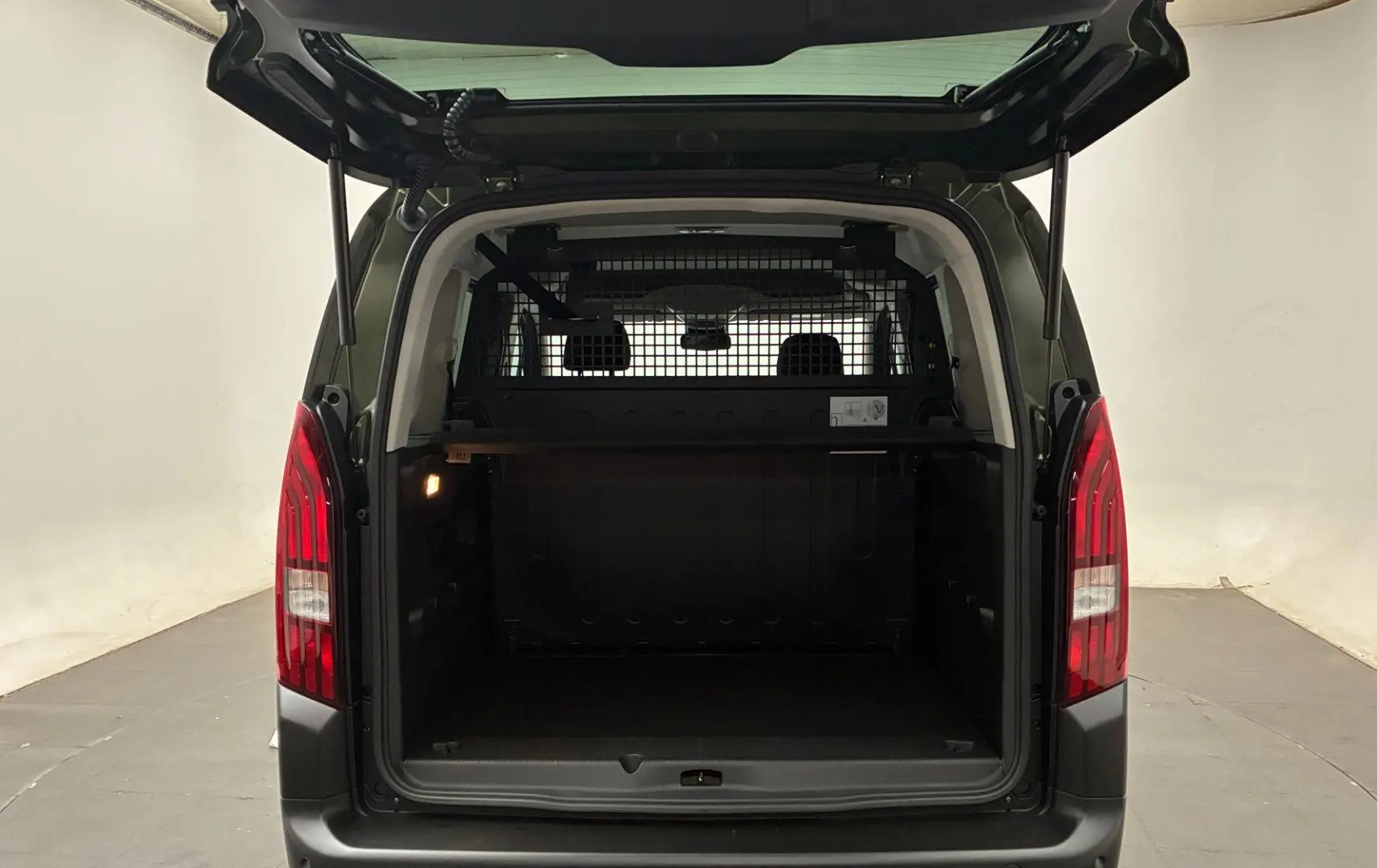 Vue arrière du Peugeot Rifter Sirkka Green 2026 avec hayon ouvert et cloison de séparation visible dans le coffre.