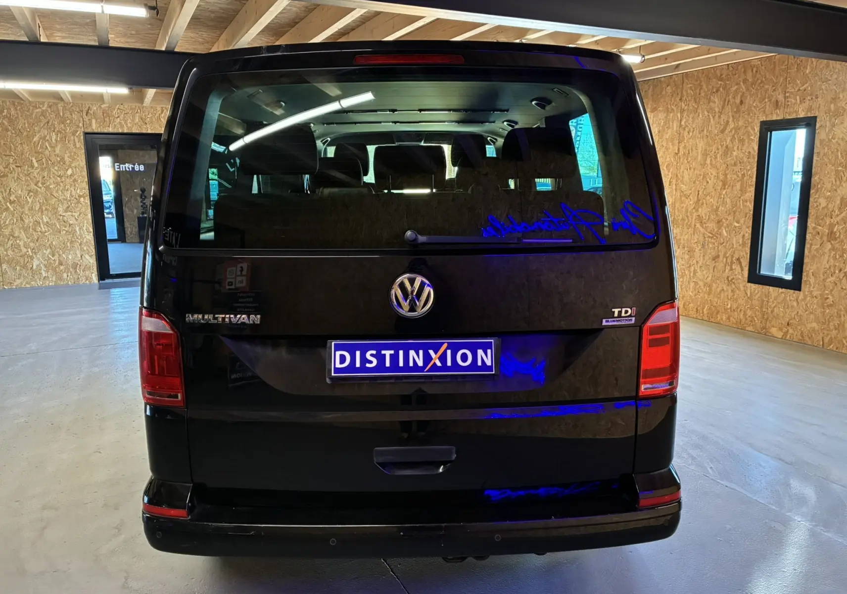 Vue arrière d’un Volkswagen Multivan T6 noir de 2015, avec badge TDI et plaque Distinxion visible en intérieur.