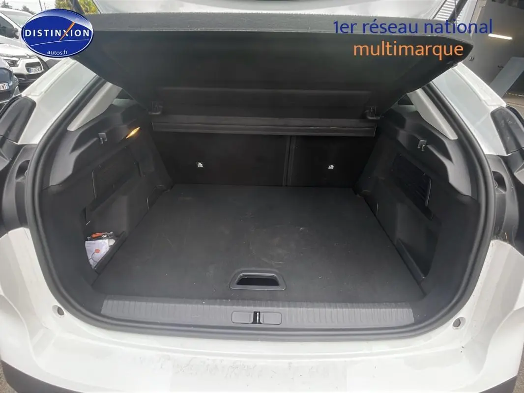 Coffre ouvert d'une Citroën C4 blanche 2022, vue arrière montrant l'espace de chargement vide et la sellerie noire.