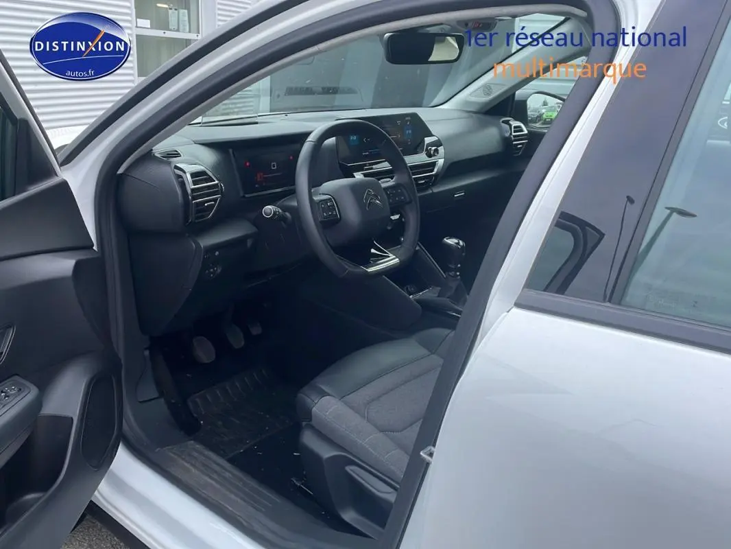Intérieur côté conducteur d'une Citroën C4 blanche 2022, montrant tableau de bord moderne et sièges gris.