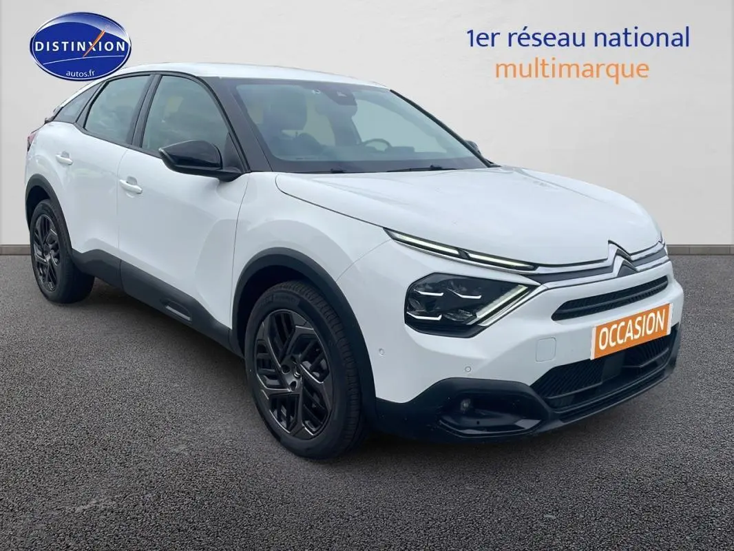 Vue 3/4 avant d'une Citroën C4 blanche avec jantes alliage noires et calandre distinctive moderne.