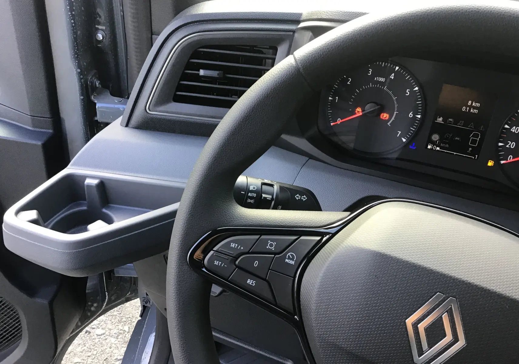 Vue intérieure côté conducteur du tableau de bord et volant du Renault Master gris urbain avec commandes au volant.