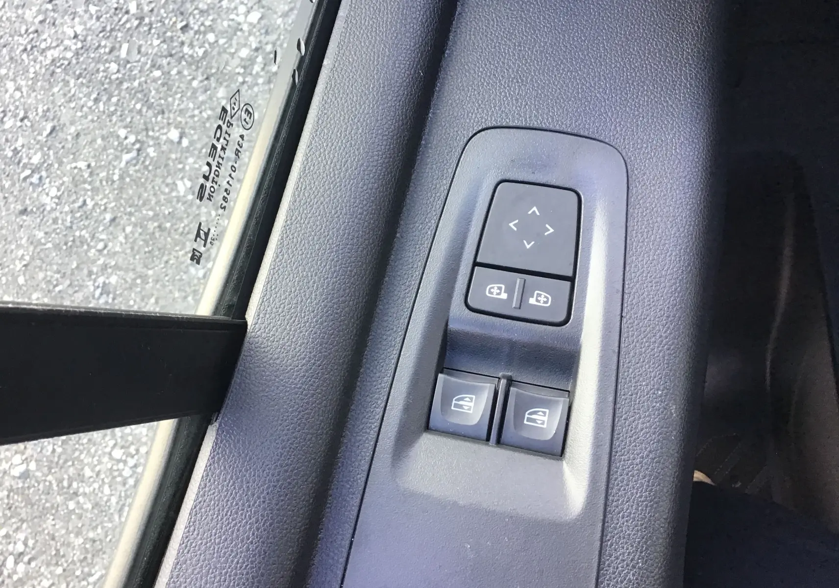 Gros plan sur les commandes de réglage des rétroviseurs et vitres électriques côté conducteur du Renault Master gris urbain 2025.