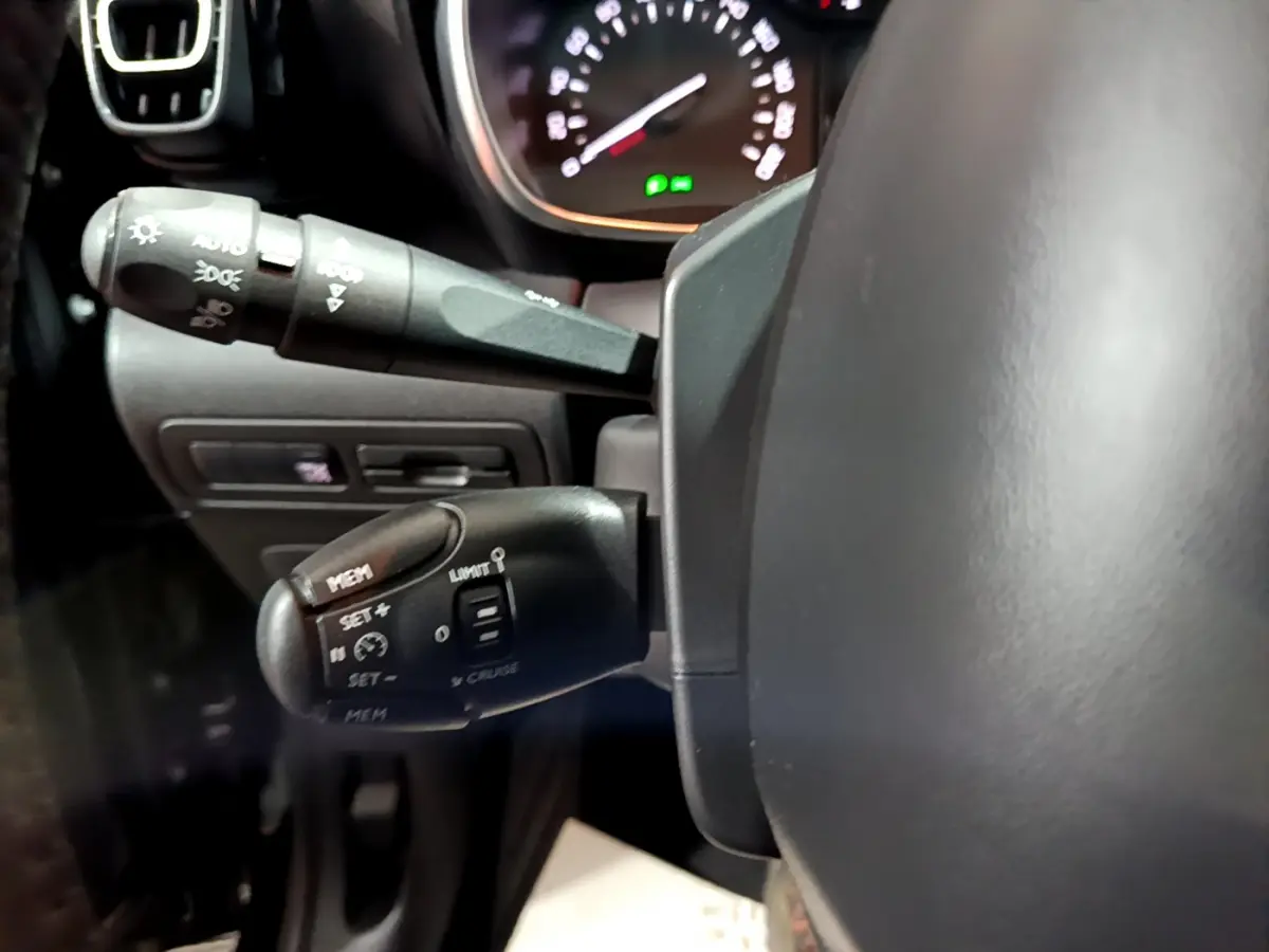 Gros plan sur les commandes au volant côté gauche du Citroën C3 Aircross noir, montrant les fonctions régulateur et limiteur de vitesse.