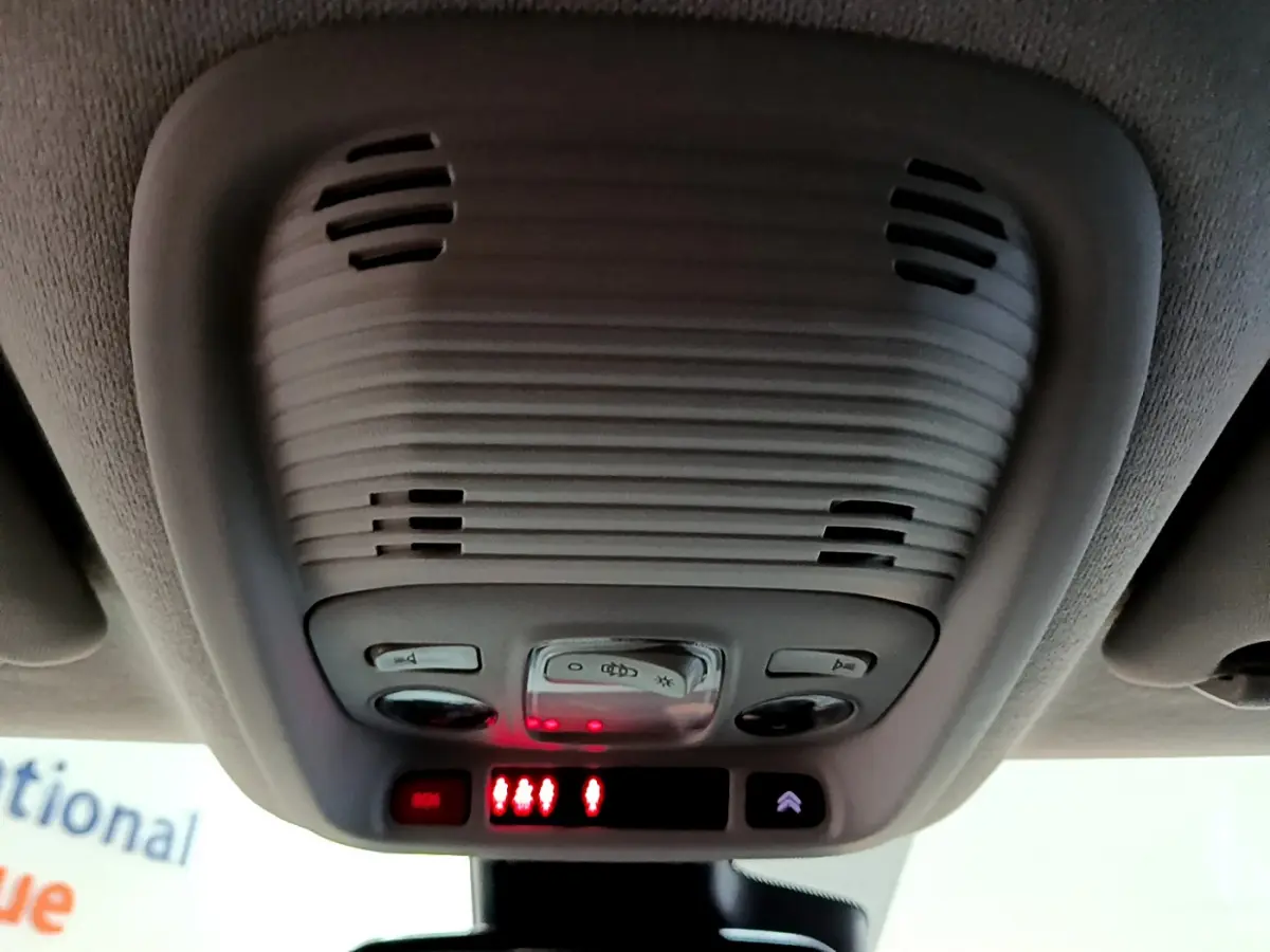 Vue en gros plan du plafonnier gris clair avec commandes d’éclairage et alertes rouges à l’intérieur d’un Citroën C3 Aircross noir.