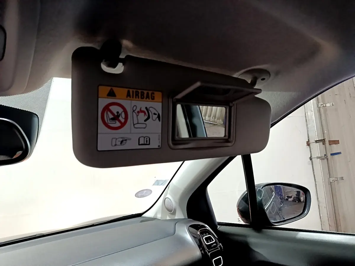 Détail intérieur du pare-soleil côté conducteur avec miroir et avertissement airbag dans une Citroën C3 Aircross noire.