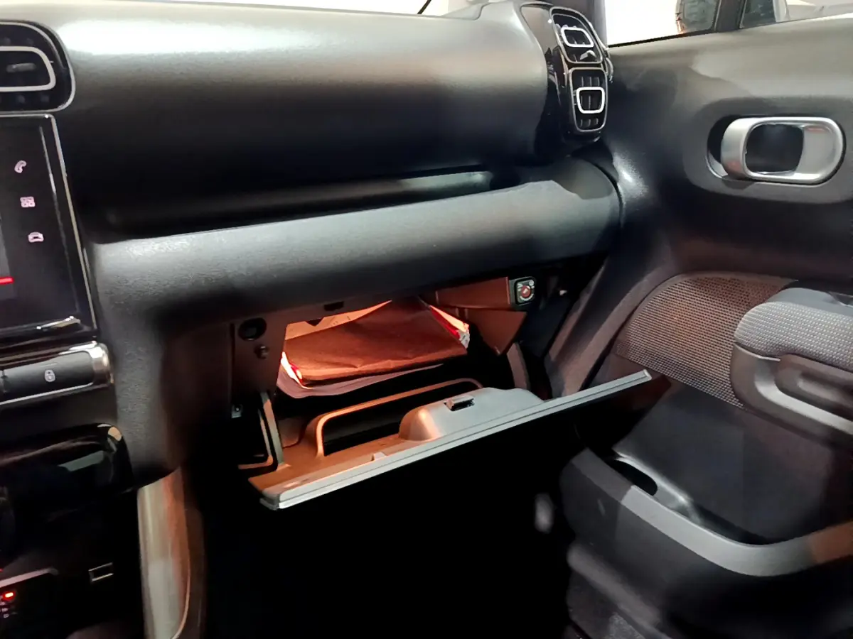 Intérieur du Citroën C3 Aircross noir 2019, vue côté passager sur la boîte à gants ouverte avec éclairage intérieur.