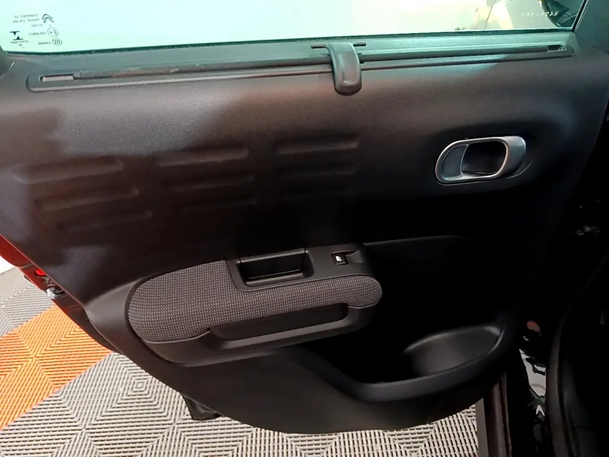 Gros plan sur la porte intérieure côté droit du Citroën C3 Aircross noir, avec poignée argentée et accoudoir texturé.