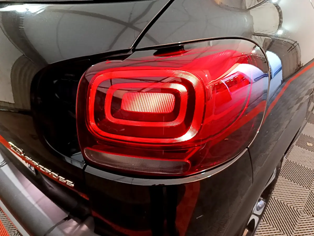 Gros plan sur le feu arrière droit rouge d'un Citroën C3 Aircross noir, avec reflet de l'environnement intérieur.